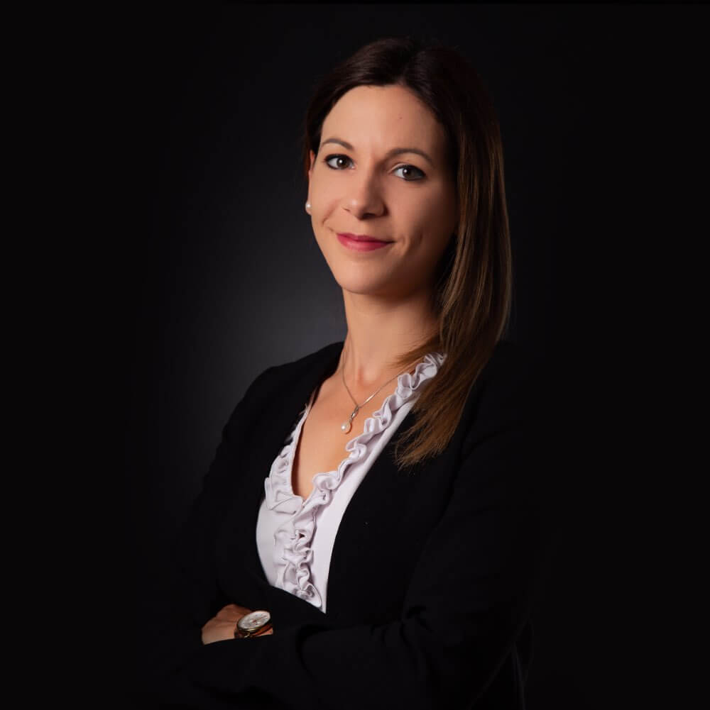 Portrait d'une femme souriante en tenue professionnelle.