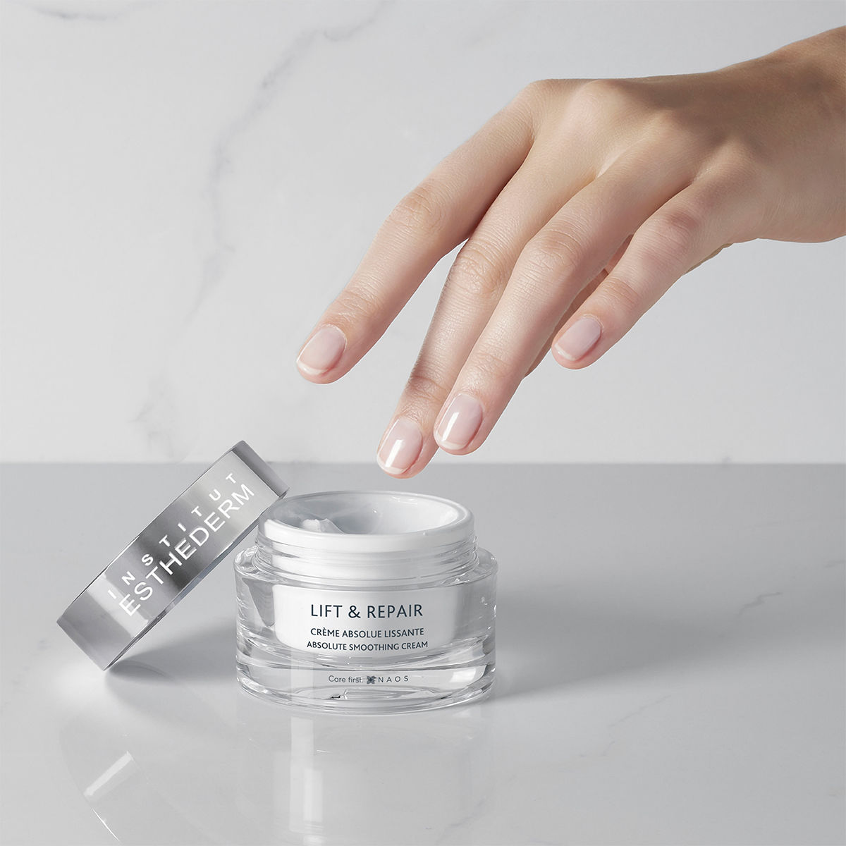 Crème anti-âge Institut Esthederm, main avec pot.
