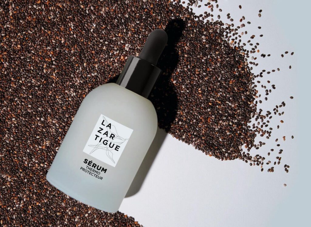 Sérum thermoprotecteur Lazartigue sur graines noires dispersées.